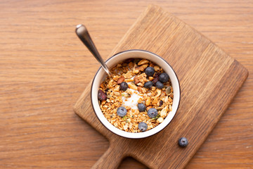 Homemade granola bowl with greek yogurt and blueberries on brown background, top view. Healthy energy breakfast or snack