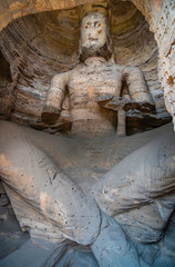 Ancient giant sitting buddha statue carved inside the mountain cave. Yungang Buddhist Grottoes in Datong, China