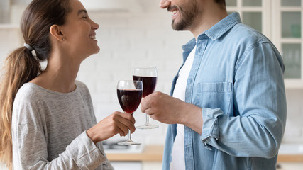 Close up happy loving couple clinking glasses of red wine, smiling wife and husband celebrating anniversary, mortgage and relocation or holiday, beautiful woman and man enjoying romantic date