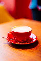 Close-Up Of Cappuccino latte in red cup on wooden table. Coffee break. Lunch time. 