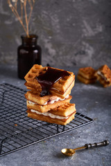 delicious homemade Vienna waffles with syrup served on a gray table Vertical