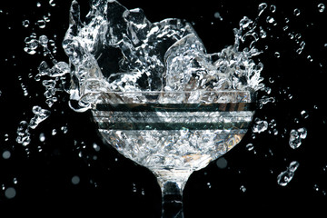 Ice cubes splashing into glass of water, isolated on white