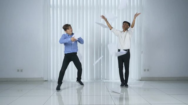 Two business people dances and throws paperwork