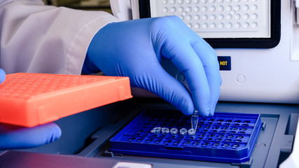 Loading a DNA tube into a PCR (polymerase chain reaction) thermocycler machine in a bioscience...