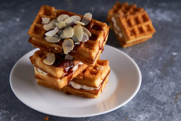 delicious homemade Vienna waffles with syrup and almond crumbs served on a gray table