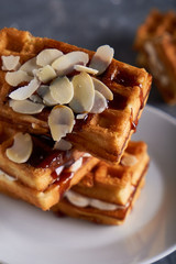 delicious homemade Vienna waffles with syrup and almond crumbs served on a gray table