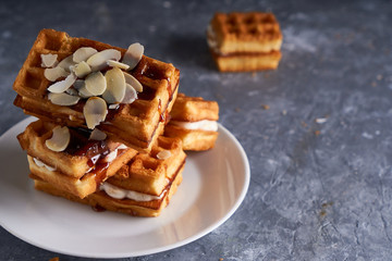 delicious homemade Vienna waffles with syrup and almond crumbs served on a gray table