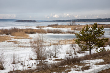 Dark spring ice on the big Kama River, islands and coastal vegetation