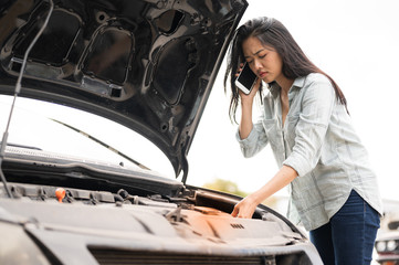 Asian young woman are stressed  and calling car insurance.Broken down car while traveling.Black long hair woman talking on cellphone after car breakdown trouble problem mechanic.
