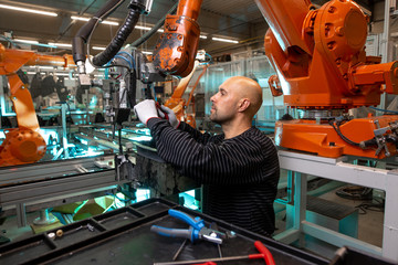 Engineer doing maintenance on a automatic robot arms in automotive industrial, smart factory