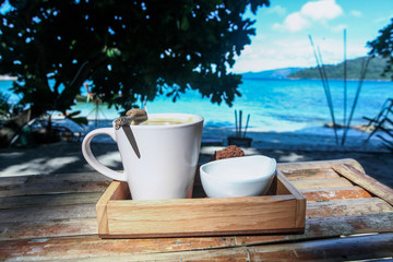 Obraz na płótnie Canvas Una taza de cafe a la orilla del mar en mesa de bambu
