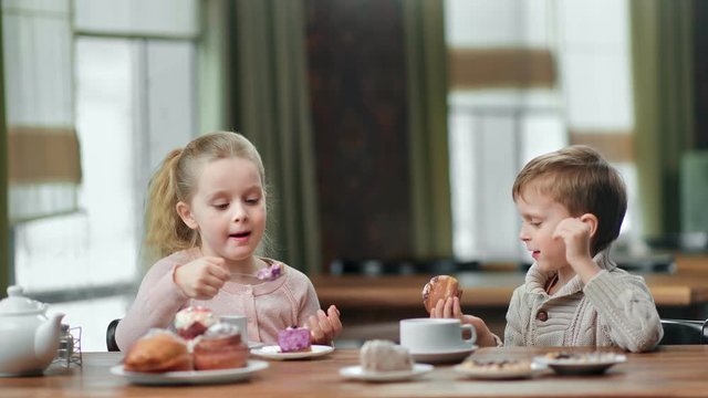 Funny girl and boy kid communicating eat delightful breakfast at cafeteria. 4k Dragon RED camera
