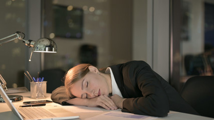 The Young Businesswoman having Nap at Office Desk at Night