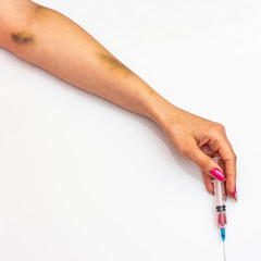 Female hand with bruises from injecting drugs with a syringe.