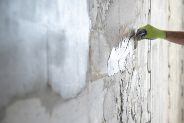 Worker builder hand applied gypsum plaster to smooth surface. Apartment repair concept