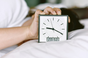 Sleepy girl's hand showing alarm clock and waking up late in the morning, Woman sleep in and laying...