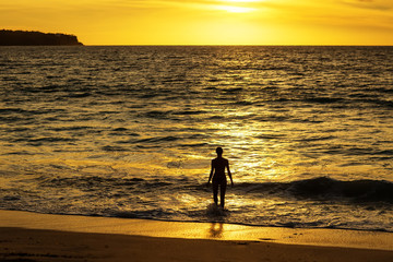 Fototapeta na wymiar Beautiful woman by the ocean at sunset
