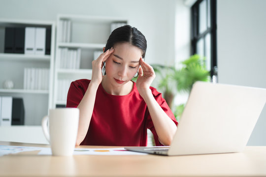Portrait of Asian beautiful office woman having headaches, stressful of work, depressed or having a fever while working at the office, concept of pressure from work, working lifestyle, stressful work.