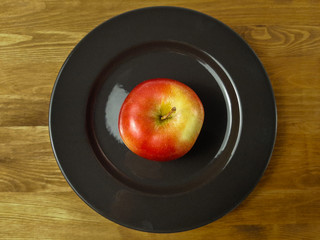 Apple on a plate on a wooden table.