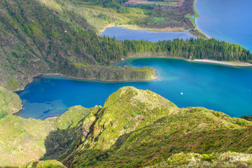 Fototapeta na wymiar Blue lagoon in volcanic crater lake on a sunny day surrounded by lush green mountains