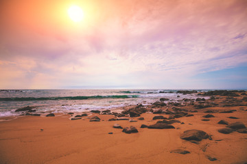Seascape in the evening. Sunset on the beach. Sandy rocky seashore with cloudy sky
