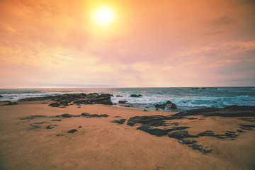 Seascape in the evening. Sunset on the beach. Sandy rocky seashore with cloudy sky