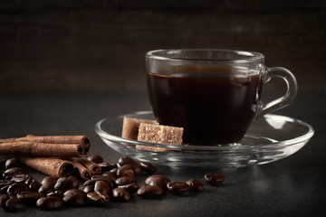 glass Cup of coffee beans with cinnamon and sugar on a dark wooden background