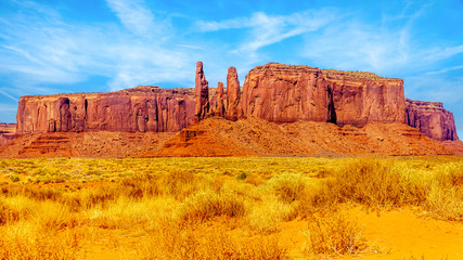 The Three Sisters and Mitchell Mesa, a few of the many massive Red Sandstone Buttes and Mesas in Monument Valley, a Navajo Tribal Park on the border of Utah and Arizona, United States