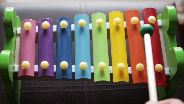 Hand Playing Colorful Toy Xylophone Music Notes red green yellow blue