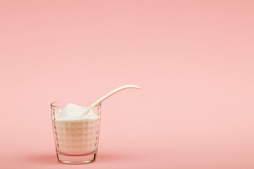 Collagen powder on pink background. Extra protein intake. Natural beauty and health supplement for skin, bones, joints and gut. Plant or fish based. Flatlay, top view. Copy space for your text.