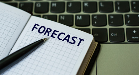 notebook with the word FORECAST , on the background of a laptop