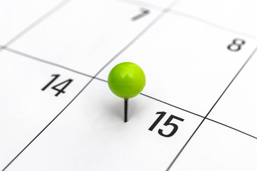 Green pinned pin in calendar on 15th day. - 330564293