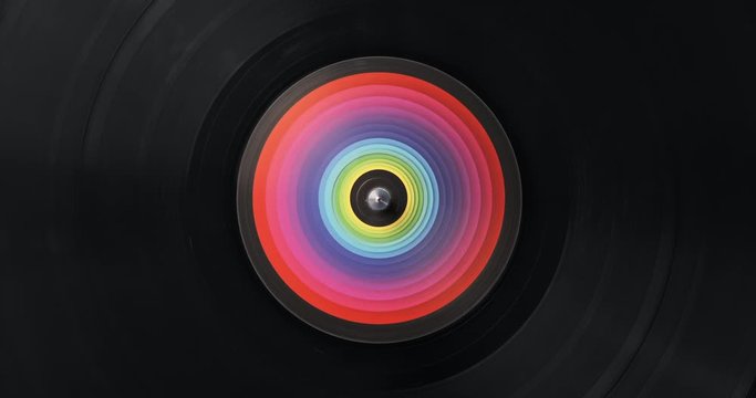 Black vinyl record DJ player. Black vinyl background with color spectrum label in center. Rotating plate close-up. Consignment. Loop. Macro Top view. Popular styles of disco from 60s, 70s, 80s, 90s