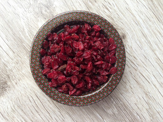 Close up of organic red Barberry in dish on wooden background. Macro shot.