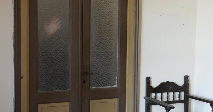 Hand appears and disappears in old house, glass door