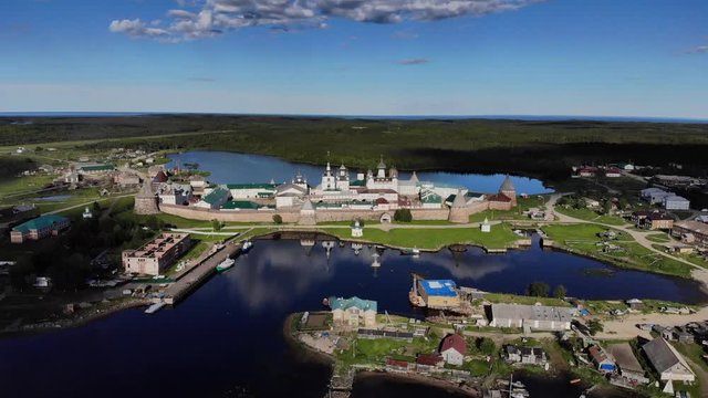 Smooth cinematic fly-by of the Solovetsky monastery from the seaside with a view over village and island on the sunny day. Solovetsky monastery is an old (1420) ROC monastery.
