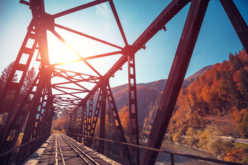 Old railway on the bridge over the mountain river in autumn