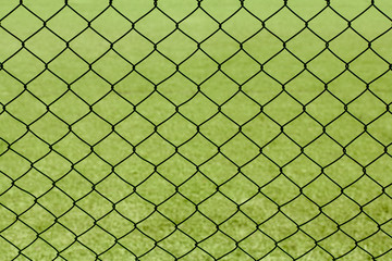 Fototapeta premium Green mesh fence against the backdrop of a sports field