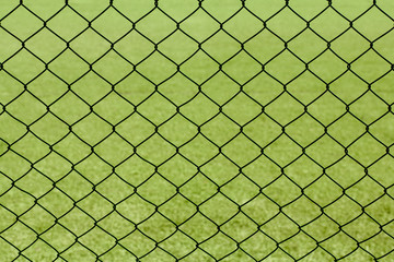 Green mesh fence against the backdrop of a sports field