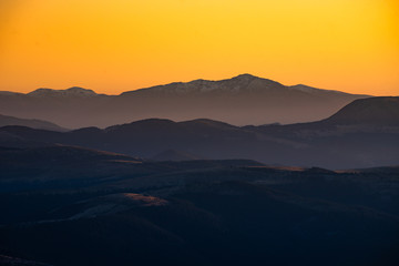 Orange and yellow sunset with mountains silhouettes. Gradient vivid nature background.