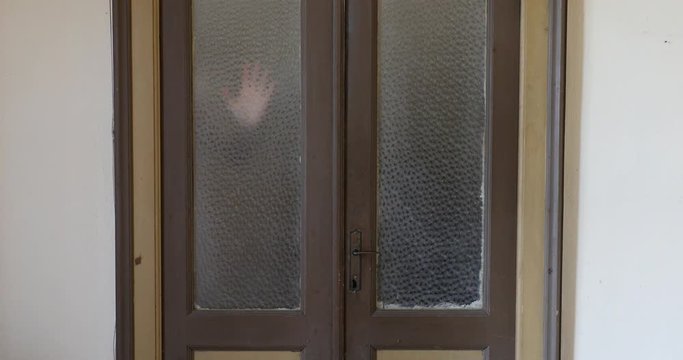 Woman hand appears and disappears in old house, glass door