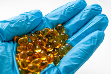 Медицина, лекарства рука в перчатке держит таблетки на белом фоне