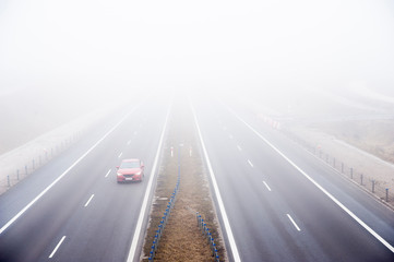 Cars ride fast on a highway in a misty cold day. Concept of road safety problem.