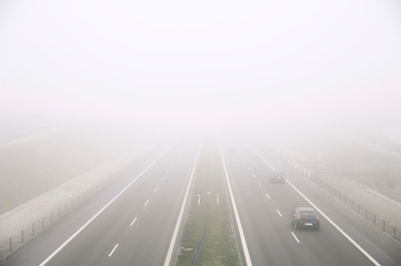 Cars ride fast on a highway in a misty cold day. Concept of road safety problem.