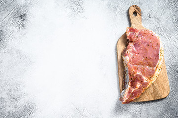 raw pork chop steak on a wooden chopping Board. Gray background. Top view. Copy space