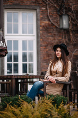 Street fashion concept. Vintage portrait of young woman in spring coat and hat. Flattering hair.