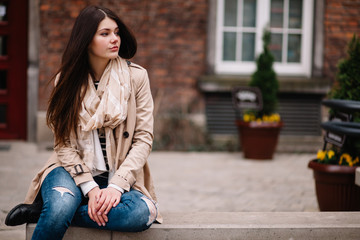 Street fashion concept. Vintage portrait of young woman in spring coat and hat. Flattering hair.