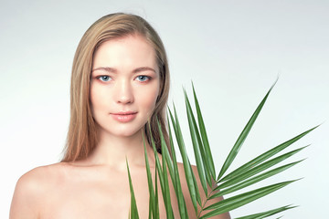 Naklejka premium Natural organic skin care, the concept of harmony with nature, green long fern leaves grass near the face. portrait of beauty ladies. Young beautiful woman with clean sparkling skin of face and body.