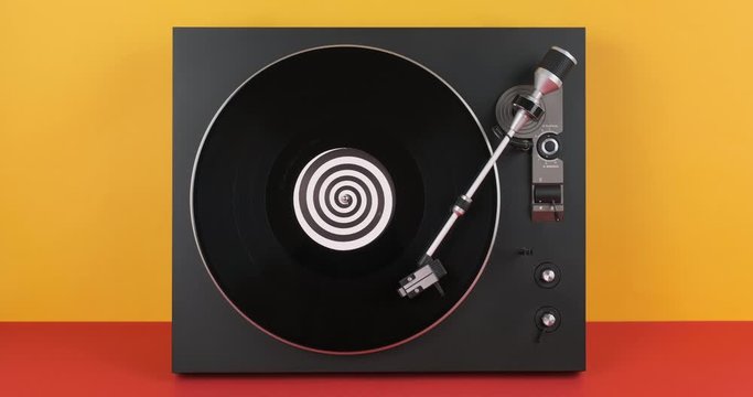 Music DJ turntable rotating black vinyl spiral label center record player on stylus needle on orange and red backgrounds. Loop. Macro Top view. Popular styles of disco 70s, 80s, 90s. Party. Club