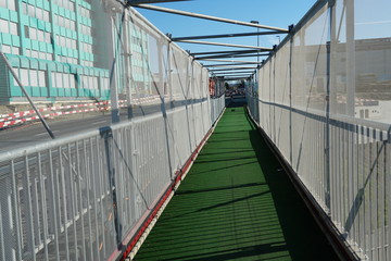 Temporary sidewalk on a building site with metal railing, covered by nets for protection and with artificial green carpet for better visibility in village Urdorf Switzerland